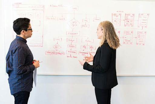 man and woman standing in front of white board