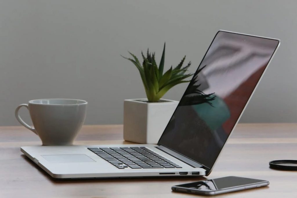 silver laptop and white cup on table 1